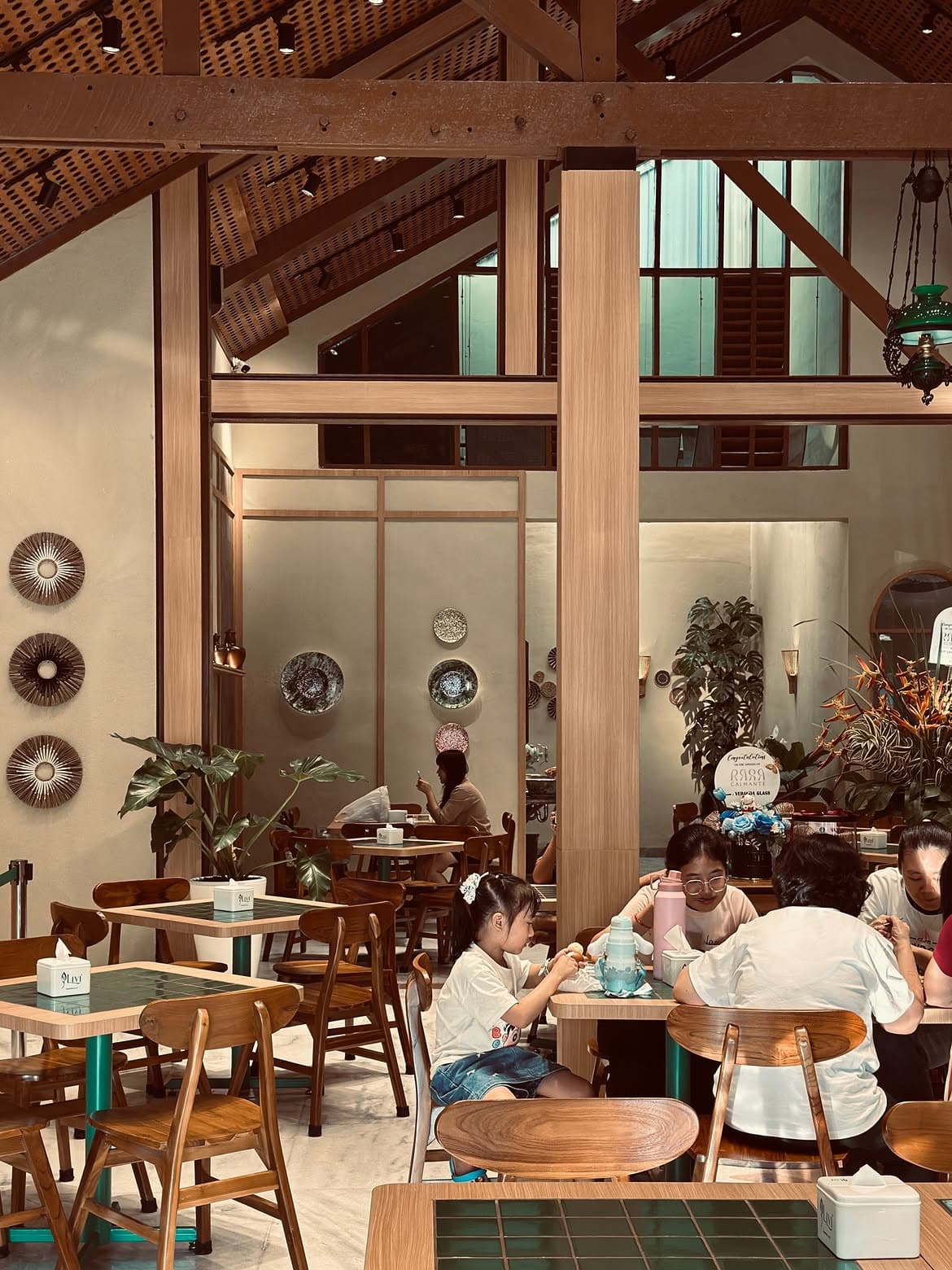 Suasana ruang makan Rasa Calmante dengan atap kayu dan keluarga yang sedang makan